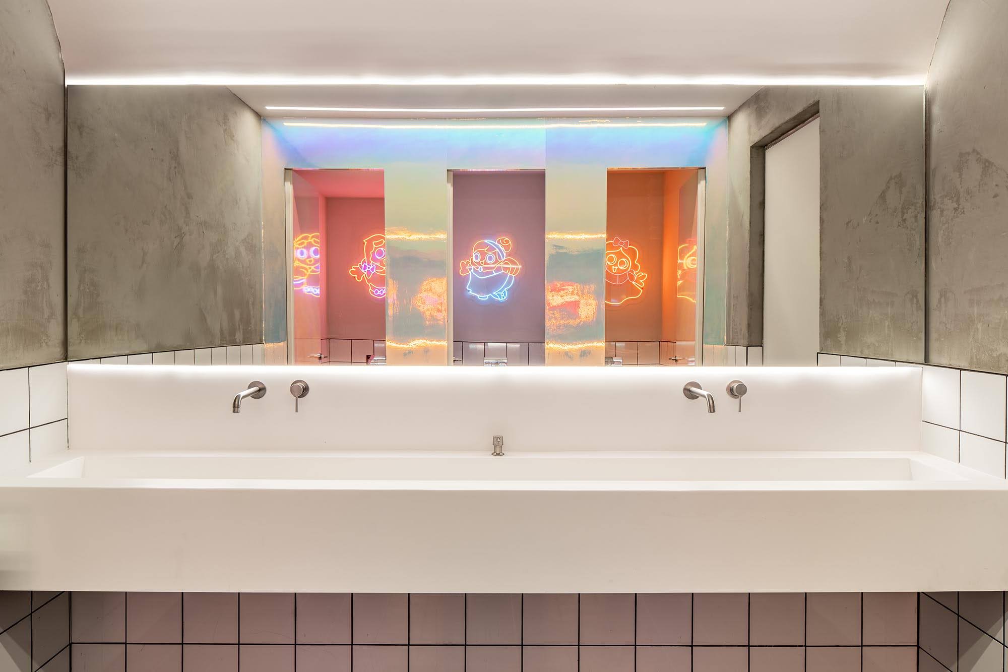 Neon character signs and neon lighting above the restroom doors