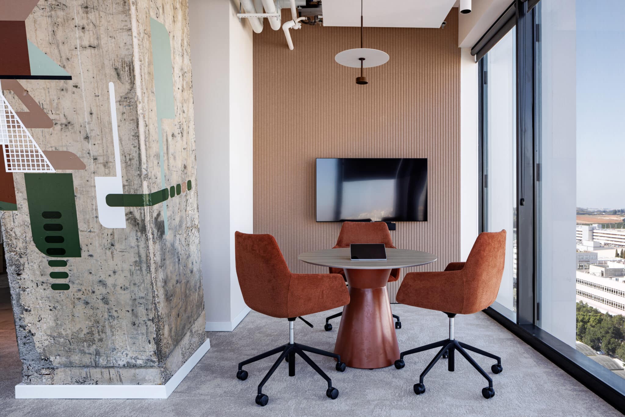 Geometric wall graphics wrapping a concrete column in a meeting corner