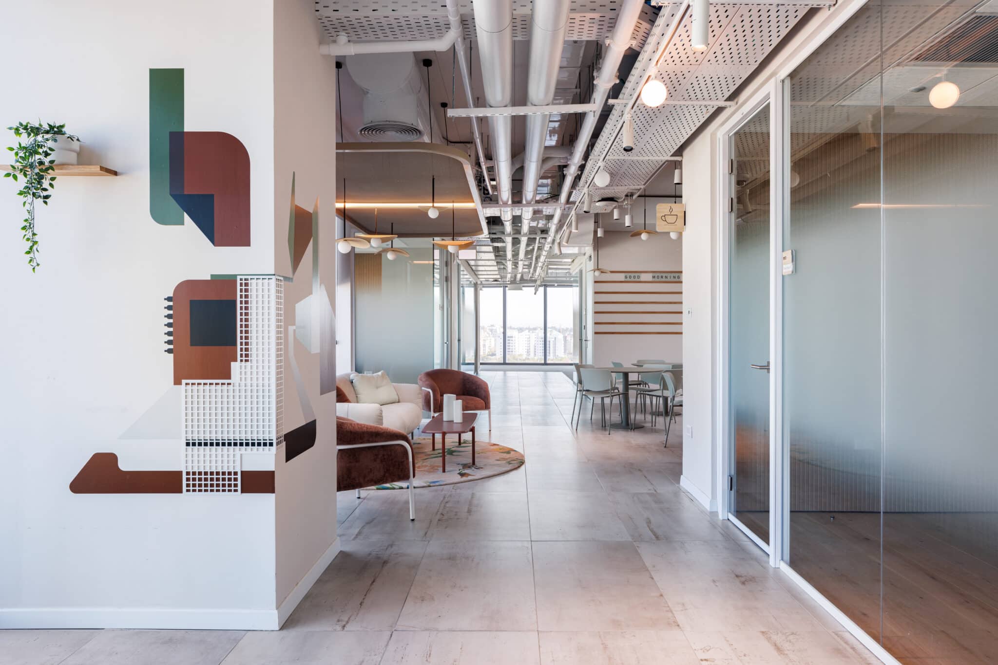 Geometric wall graphics in green and rust beside a lounge corridor