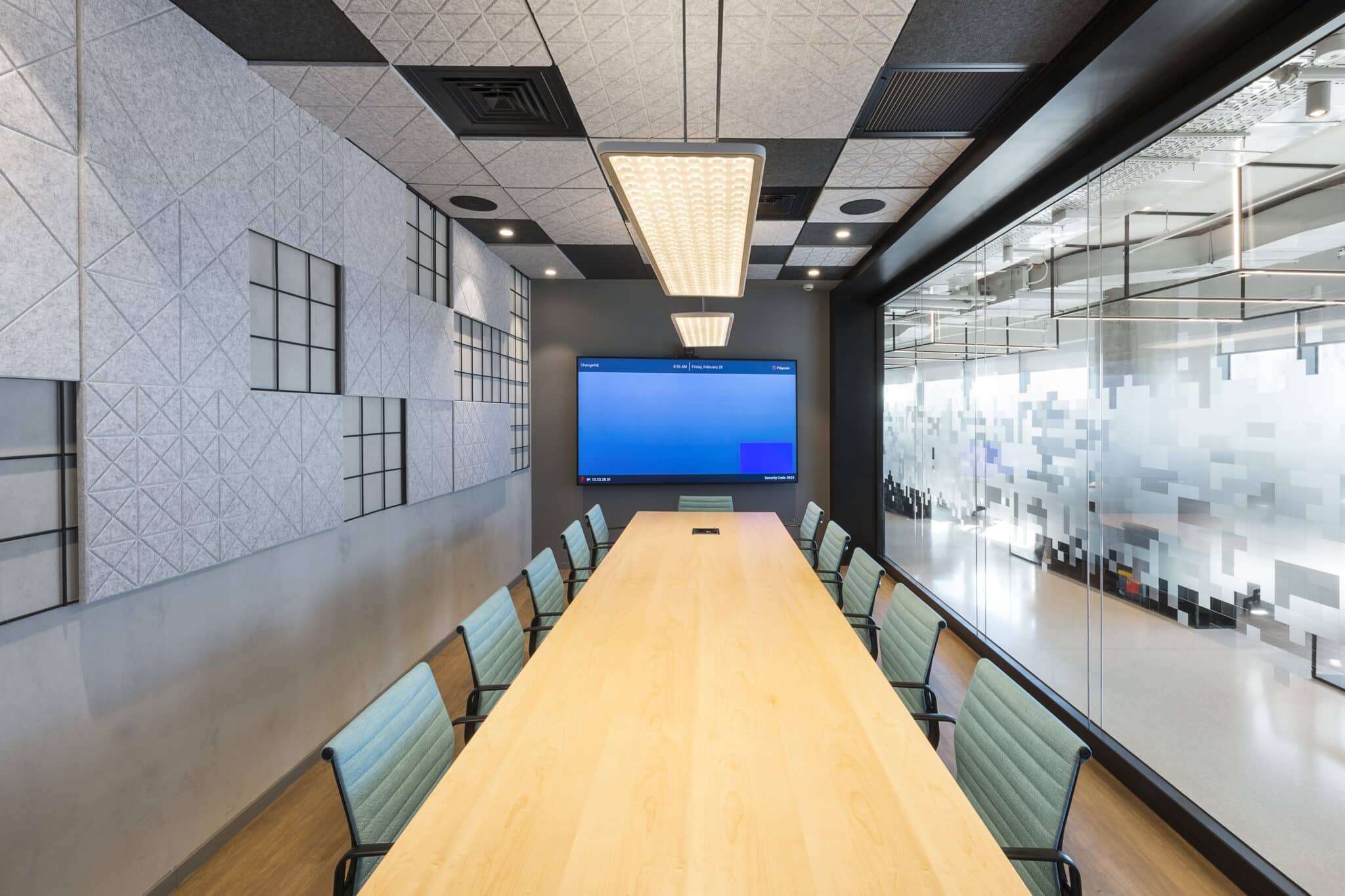 Acoustic felt wall panels and frosted glass coating in scattered pixels in a meeting room