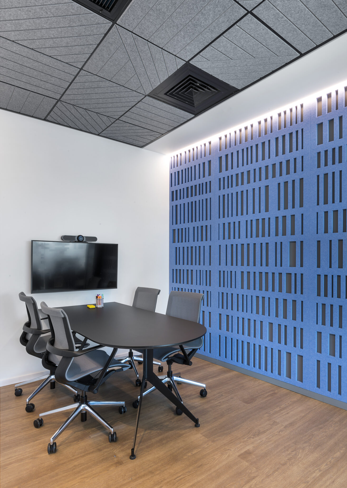 Blue acoustic felt wall with cut slots in a meeting room