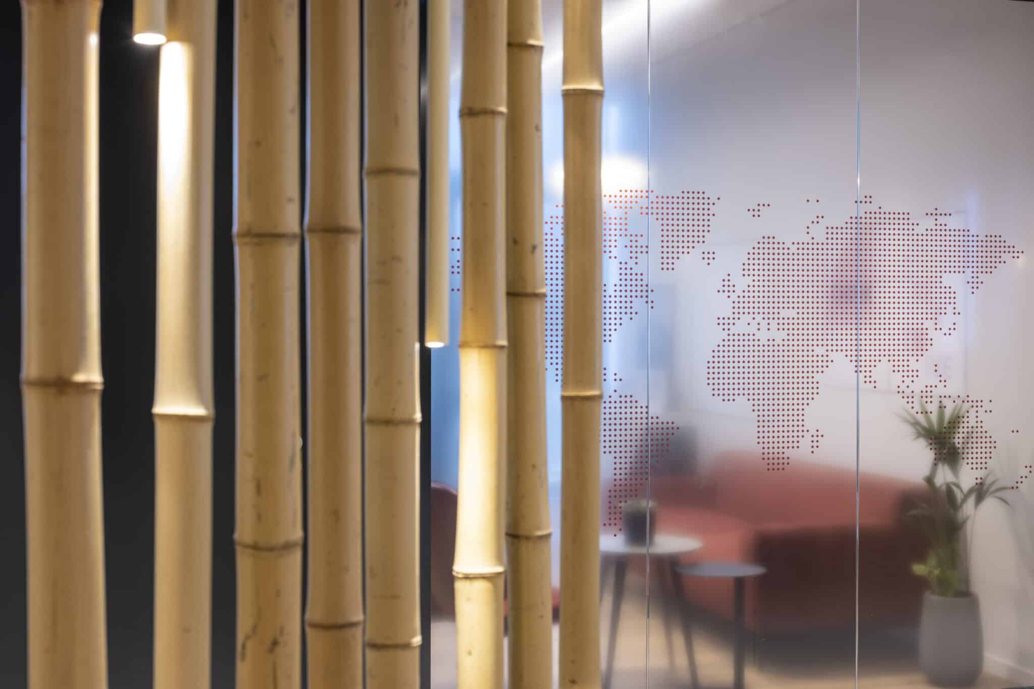 Dotted world map printed on glass behind bamboo poles