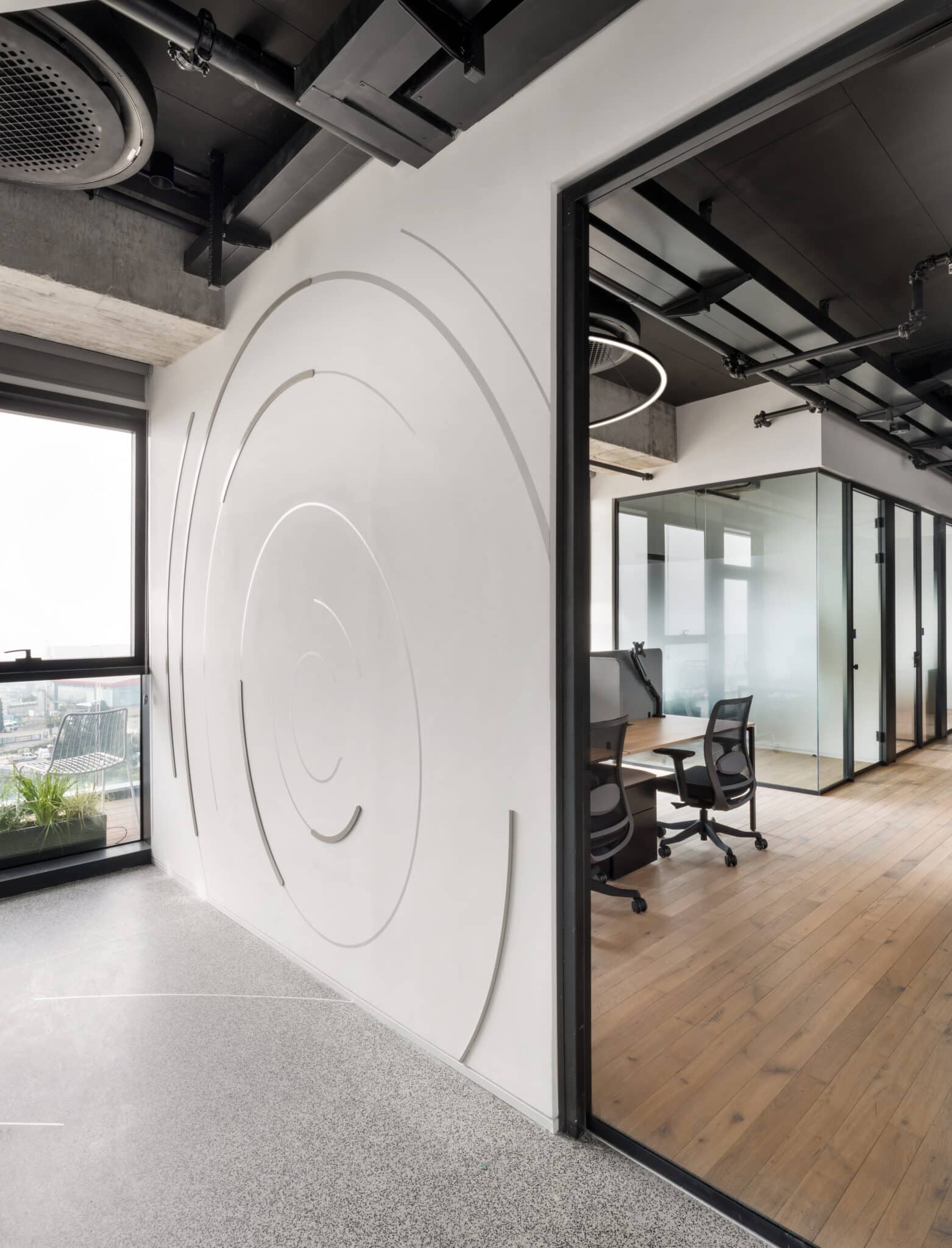 White line wall graphic in concentric circles beside a glass office
