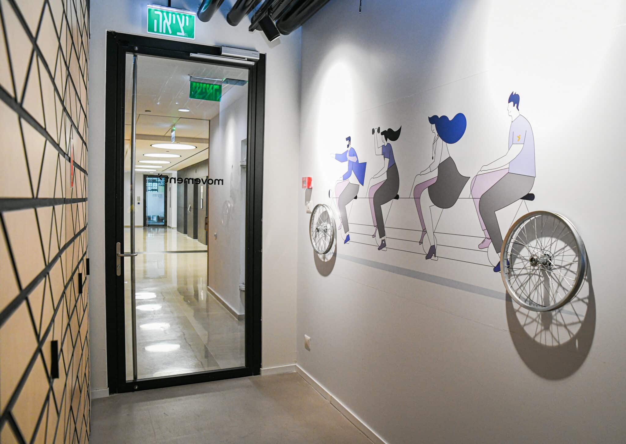 Wall graphic of four figures on a tandem bicycle in a corridor