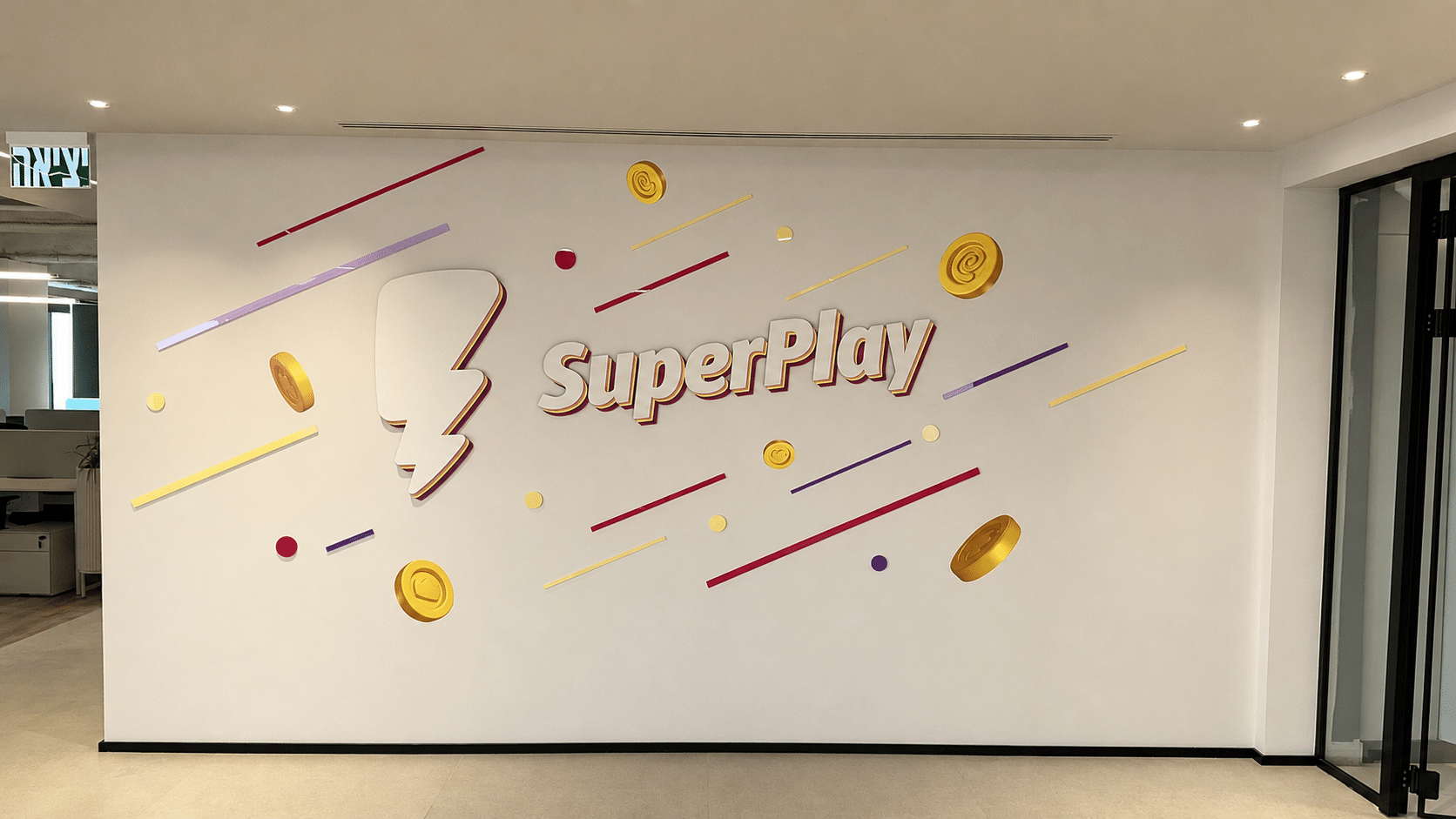 SuperPlay 3D logo with coins and confetti on a white wall