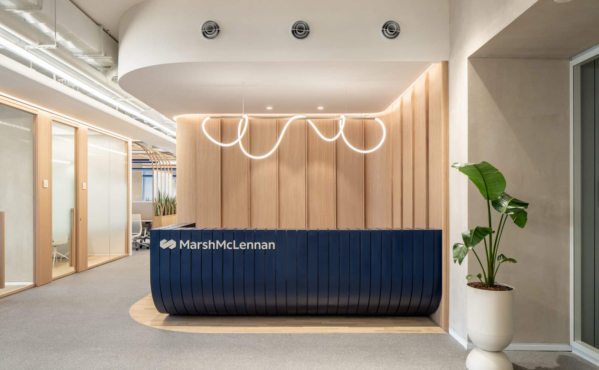 MarshMcLennan logo on a navy reception desk with a neon light above