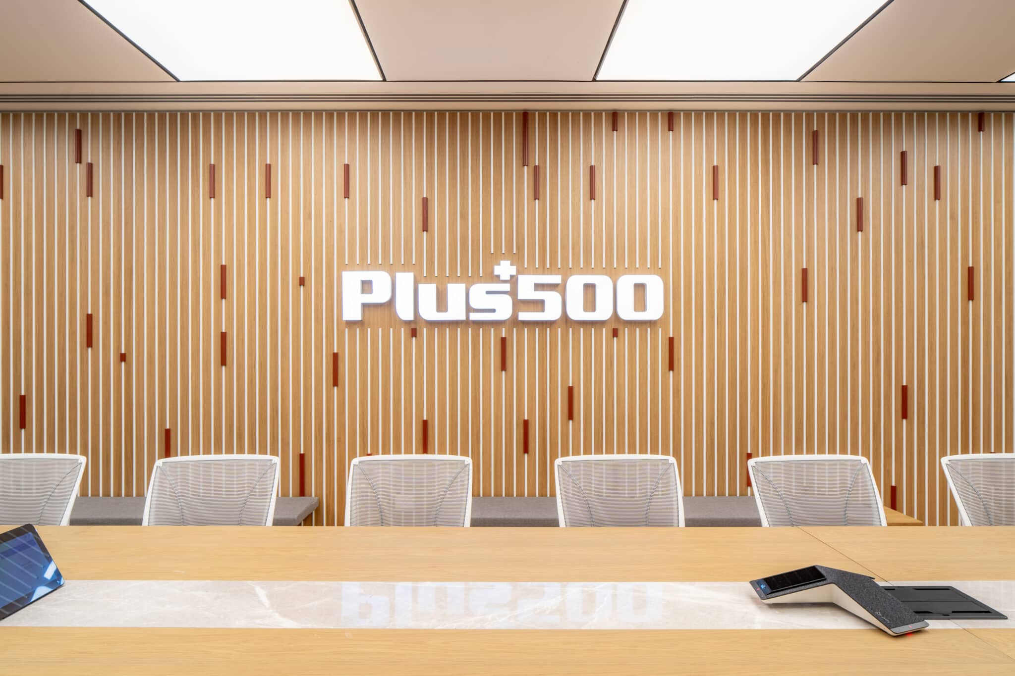 Plus500 3D logo on a slatted timber meeting room wall