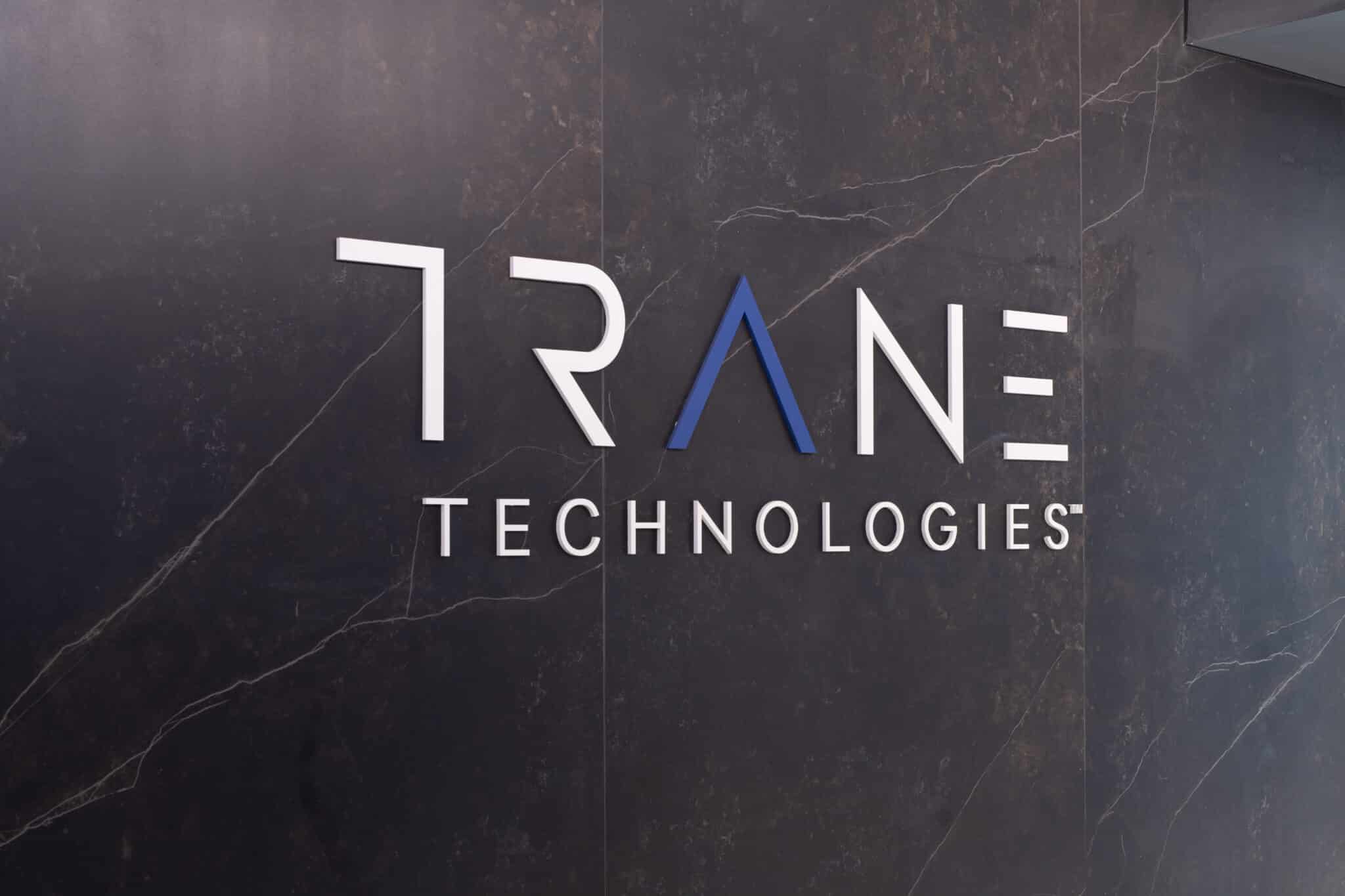TRANE TECHNOLOGIES logo in white letters on a dark marble wall