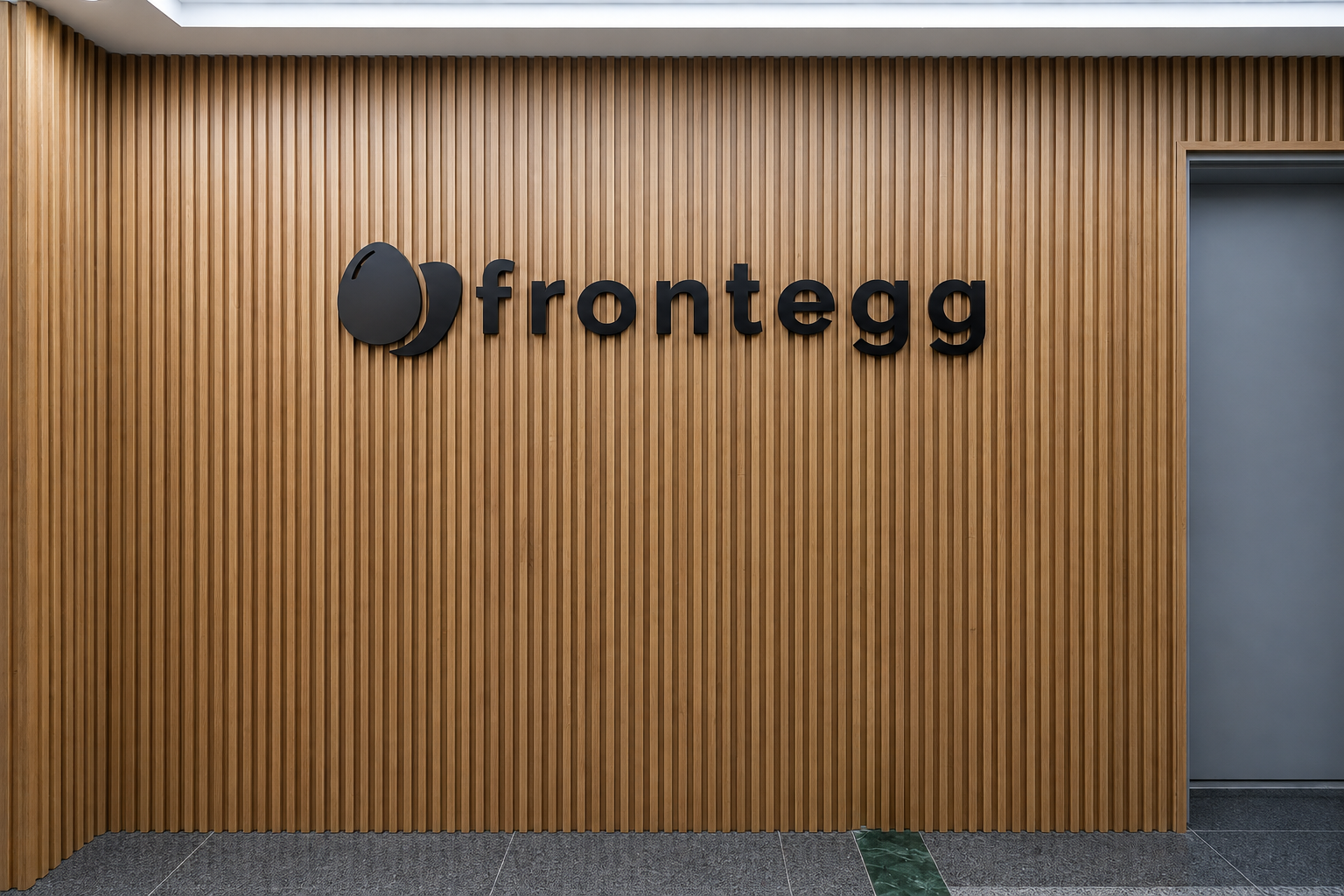 frontegg black 3D logo centred on a wood slat entrance wall