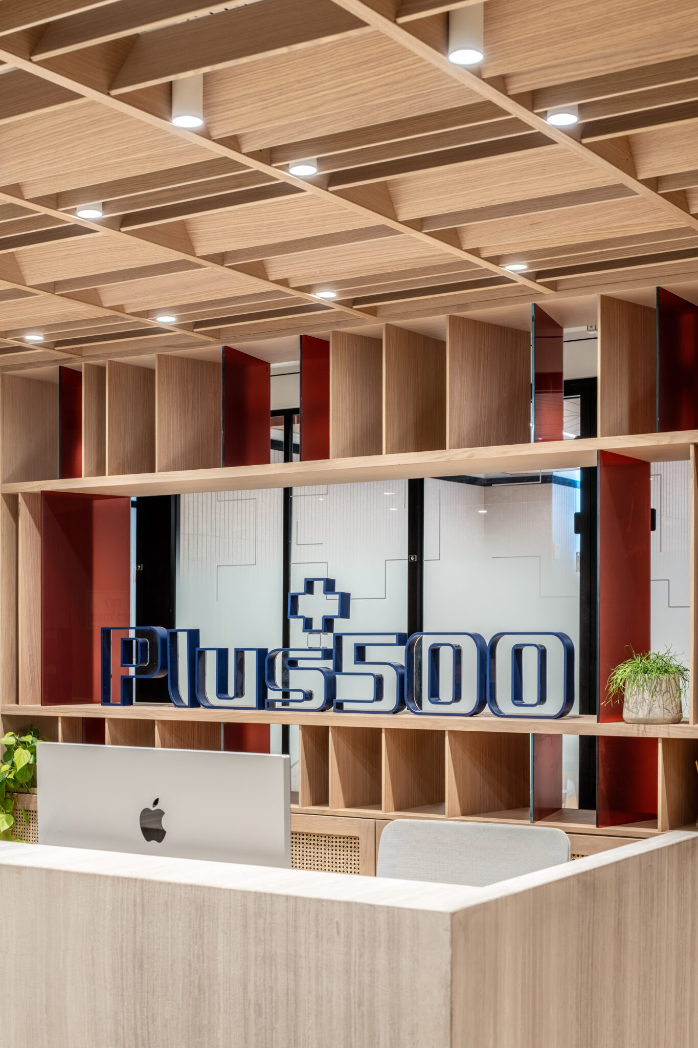 Plus500 3D logo standing on a shelf above the reception desk