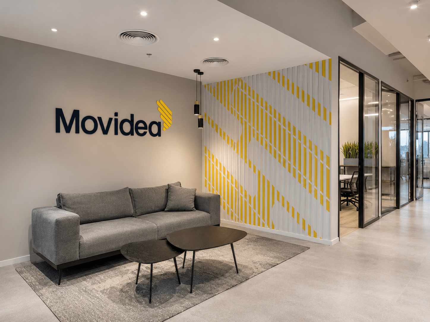 Movidea 3D logo beside a yellow striped graphic wall