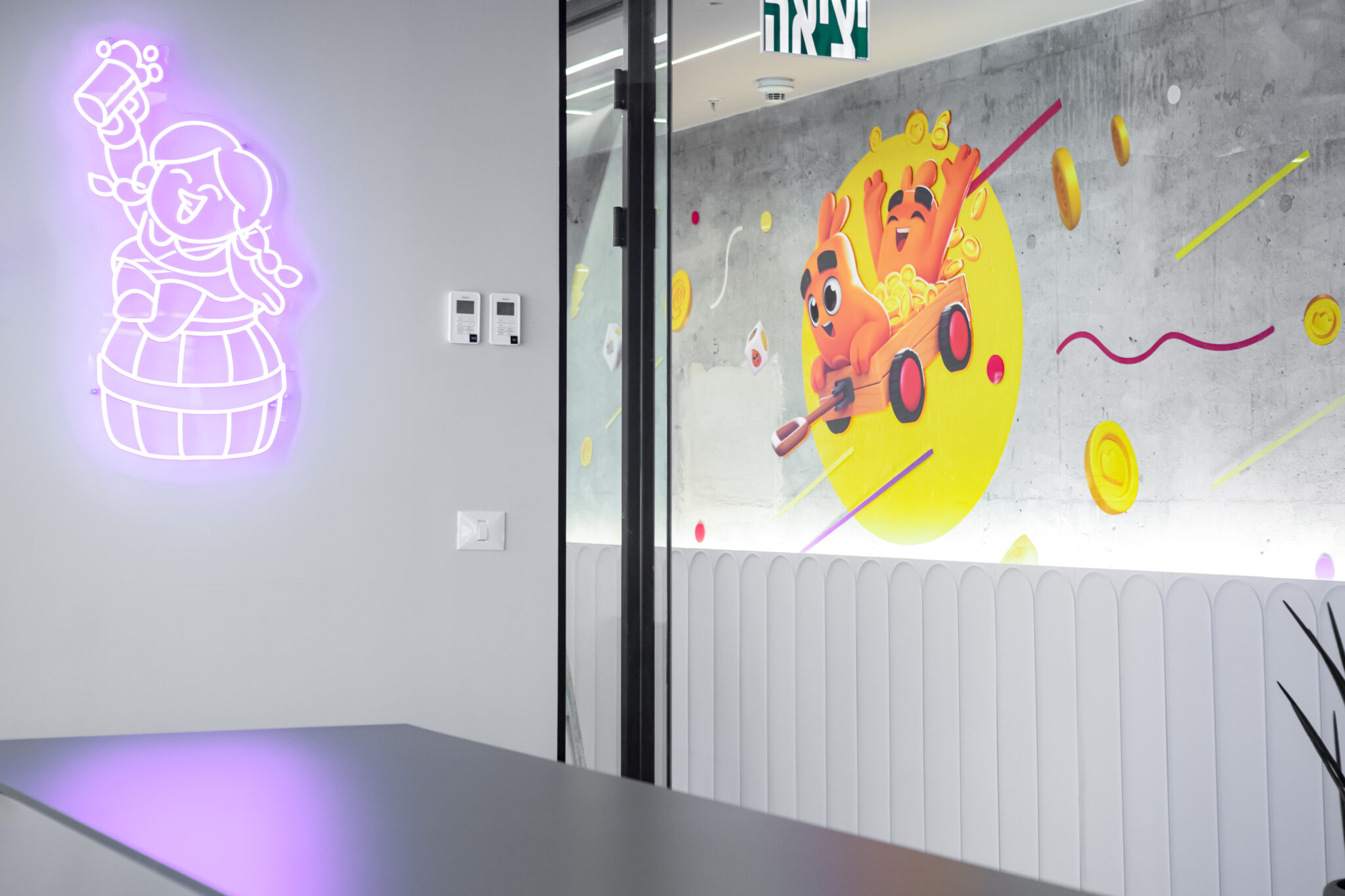 Purple neon character sign in a meeting room beside a wall graphic