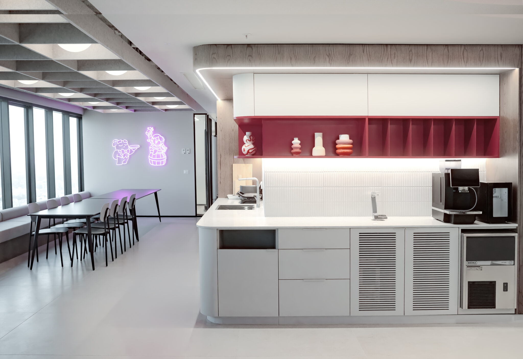 Pink neon character signs on the wall in the office kitchen